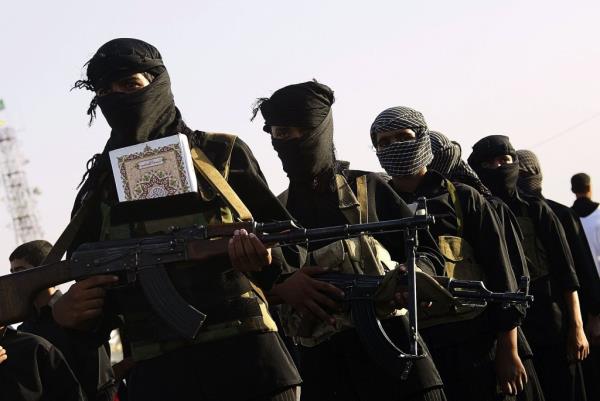 A group of armed militants wearing dark clothing and head scarves carrying automatic weapons.