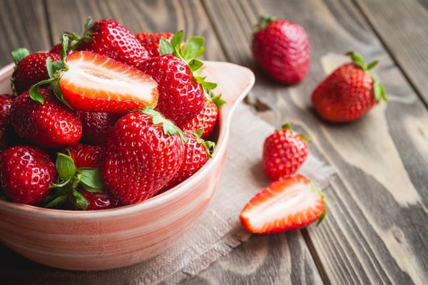 A bowl of strawberries on a wooden surface